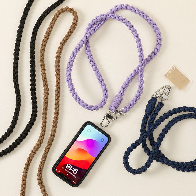 Gevlochten telefoonkoorden in zwart, camel, lila en donkerblauw naast een smartphone